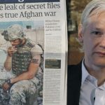 Wikileaks founder Julian Assange holds up a copy of a newspaper during a press conference at the Frontline Club in central London